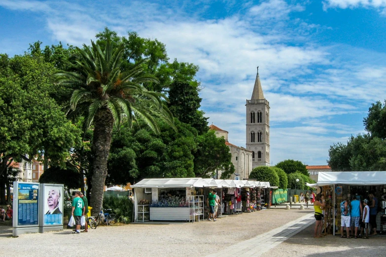 people are standing around the street market with trees in the background