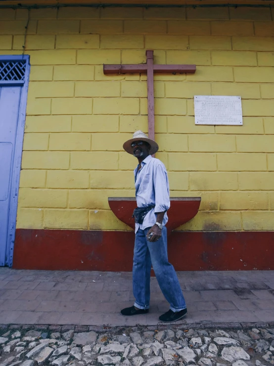 man walking past a cross on the sidewalk