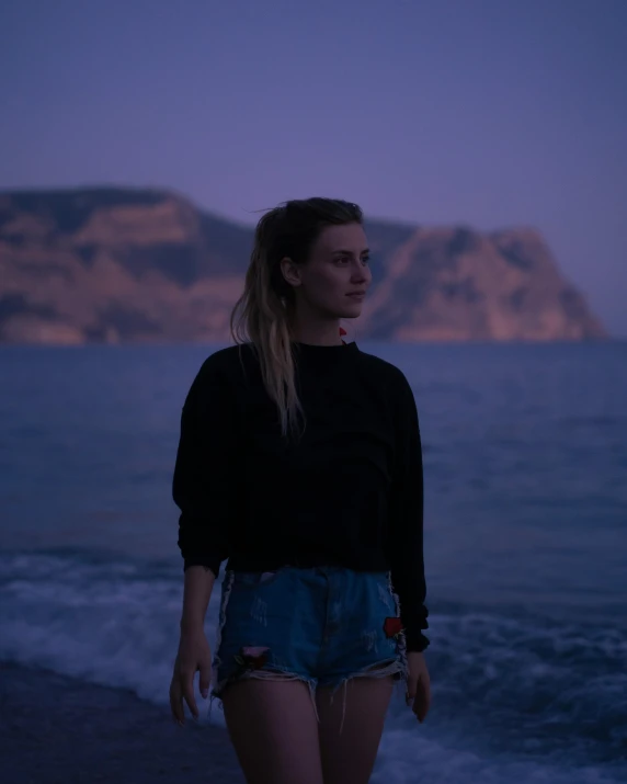 a woman standing on the beach looking back