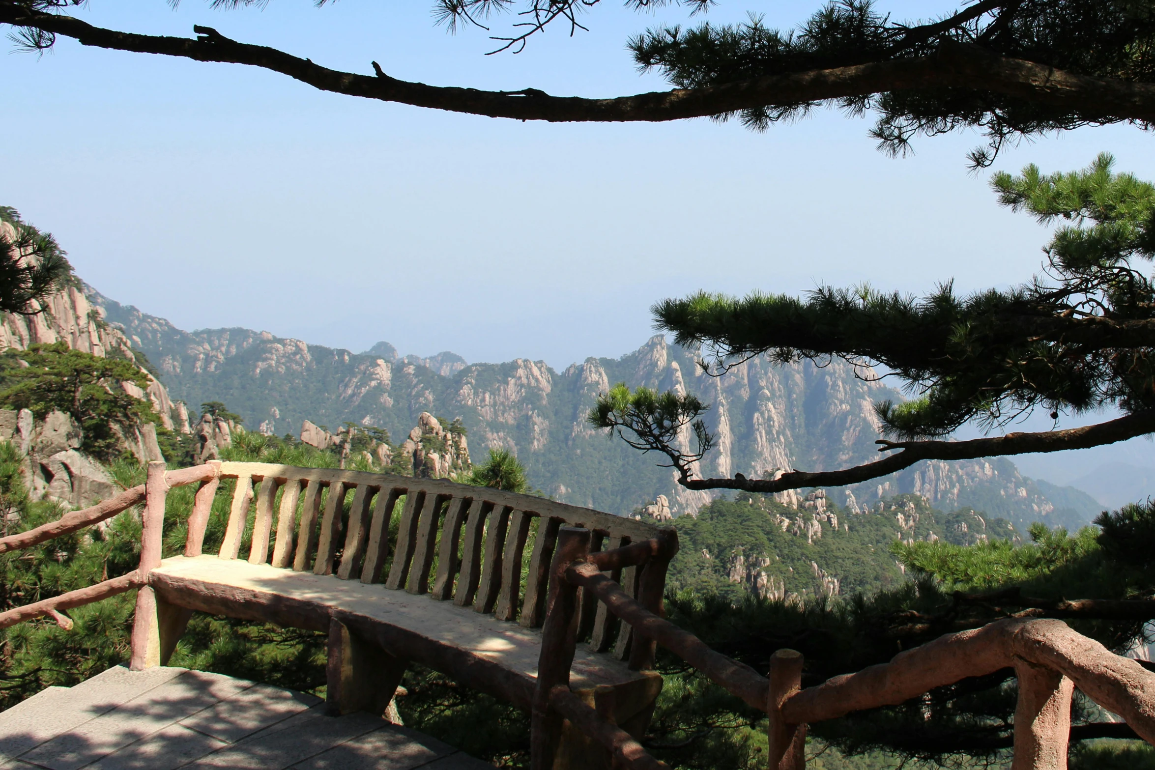 an old wooden bench overlooking some hills and trees