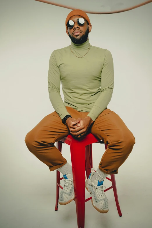 a man in tight clothes and glasses sitting on a stool