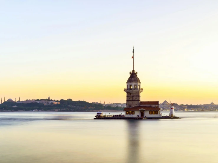 a tower in the middle of water in front of city