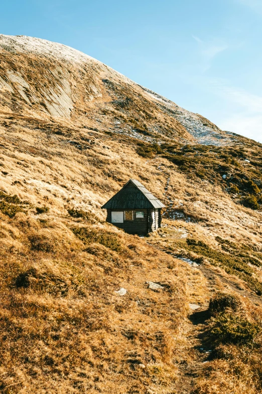 a hut on the side of a hill by a cliff