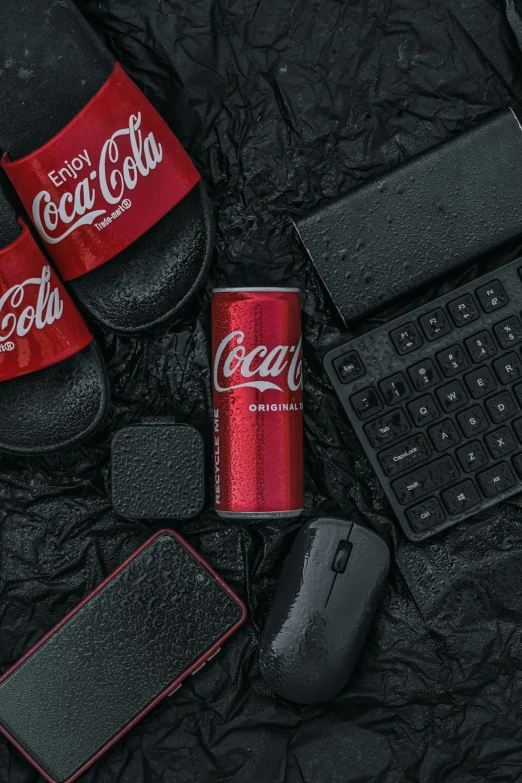 a red can of coca cola next to black keys, mouse and computer