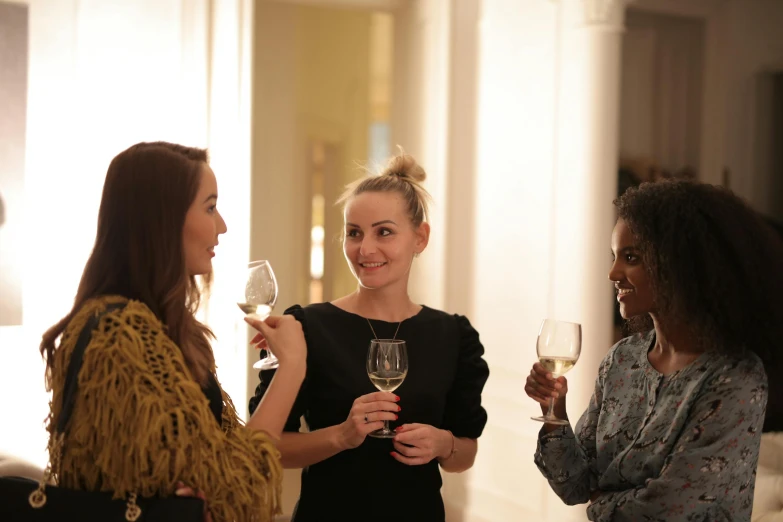 a group of women stand together with wine glasses