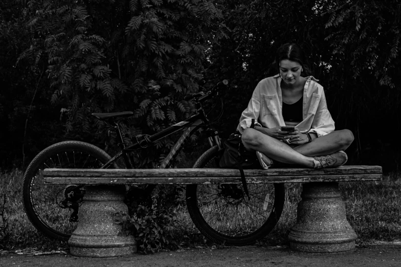 a woman with glasses on her knees sits on a bench