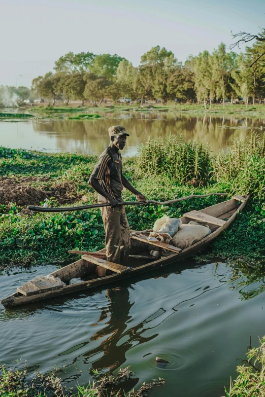 the man is standing in his boat on the water