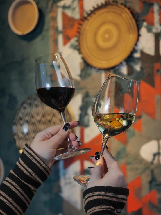 two people clinking into wine glasses with beverages inside them