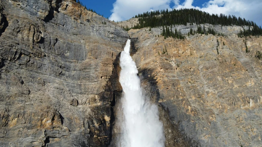 waterfall flowing out of the side of a large cliff