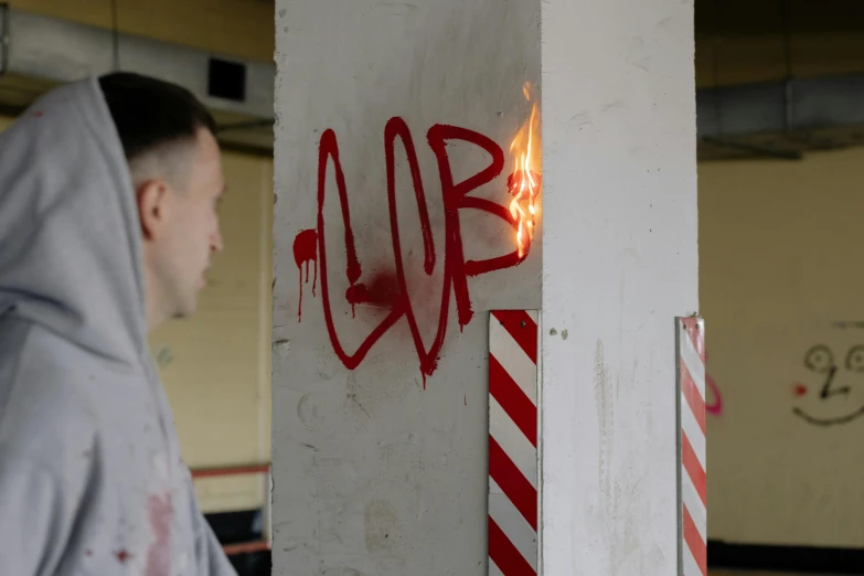 a person with a hooded jacket walking past fire