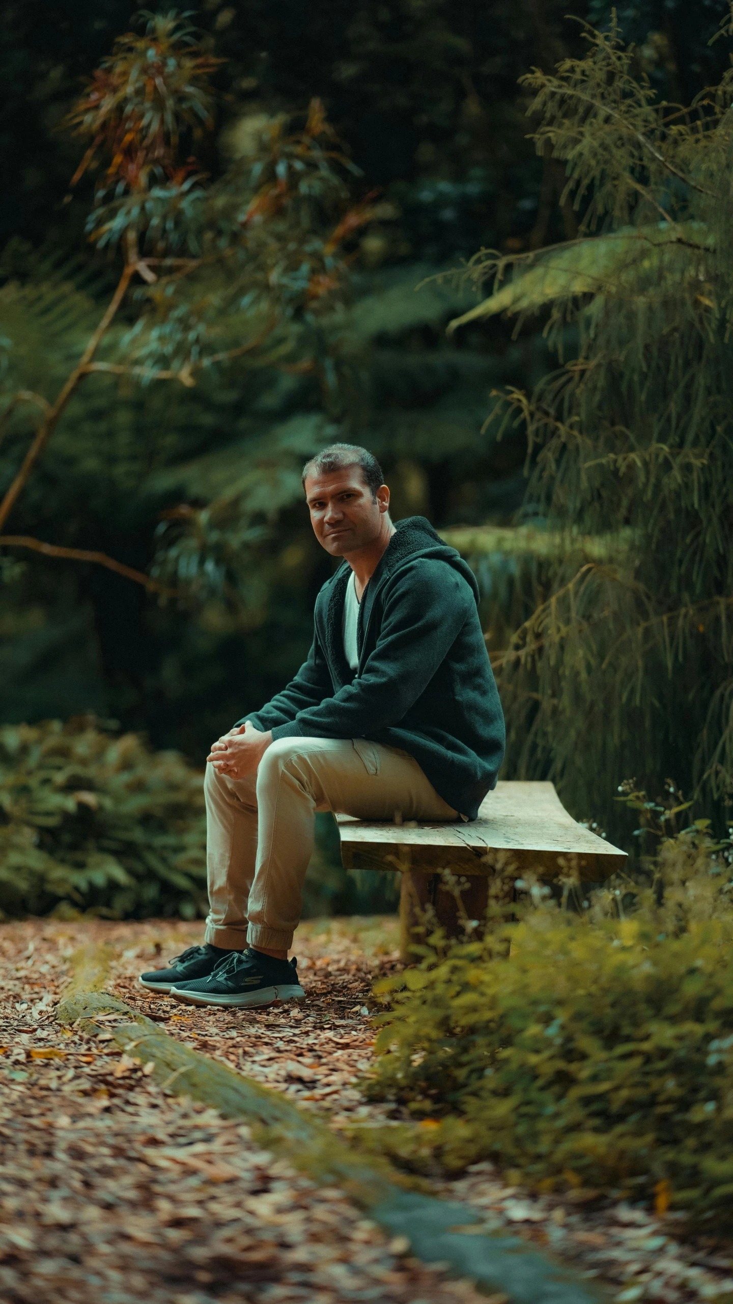 a man sitting on a wooden bench in the park