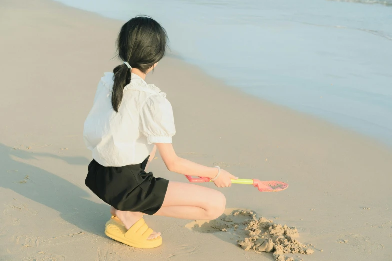 a woman kneeling down while holding onto a sand castle