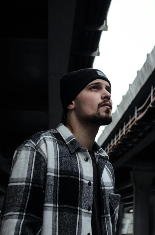 the man stands in front of an overpass with his eyes closed