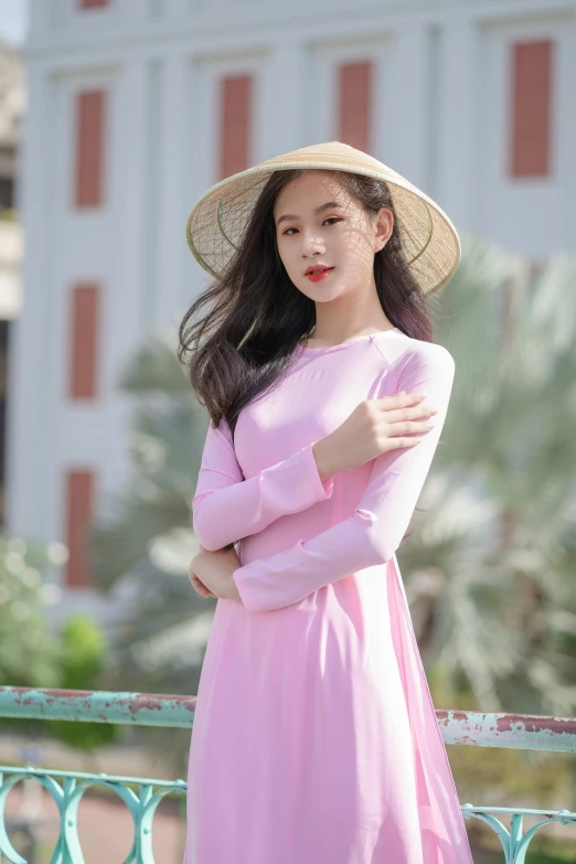 an asian woman with long dark hair wearing a pink dress, large hat and standing outdoors