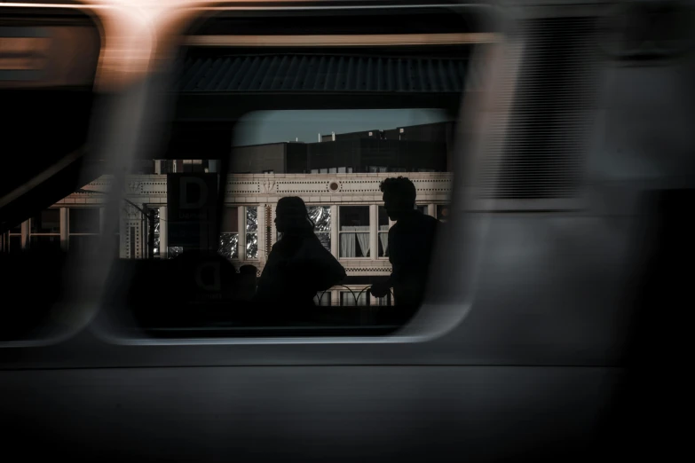 the reflection of two people in the rear window of a car