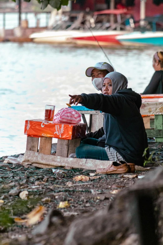 people sit near water in front of boats