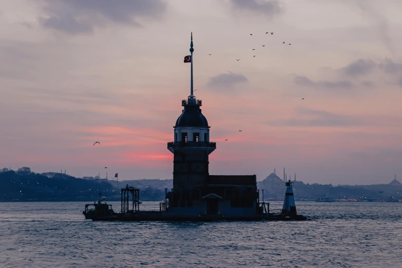 a boat sailing on water with a light house behind it