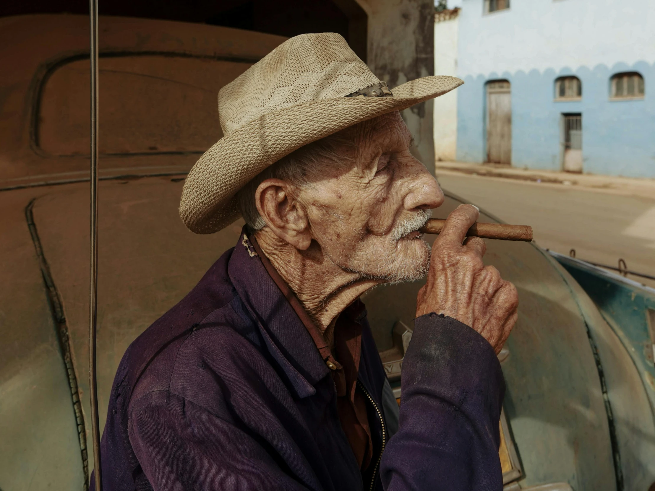 an old man sitting in the back of an old car holding a cigar