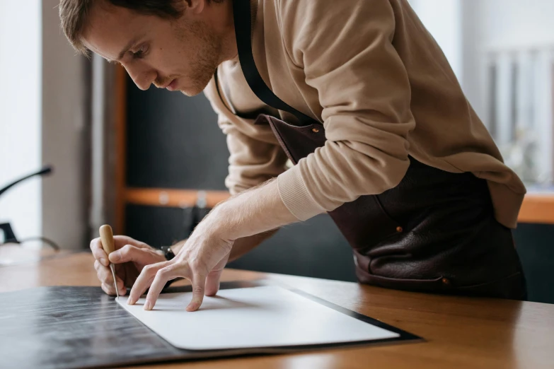 a man writing on paper at a desk