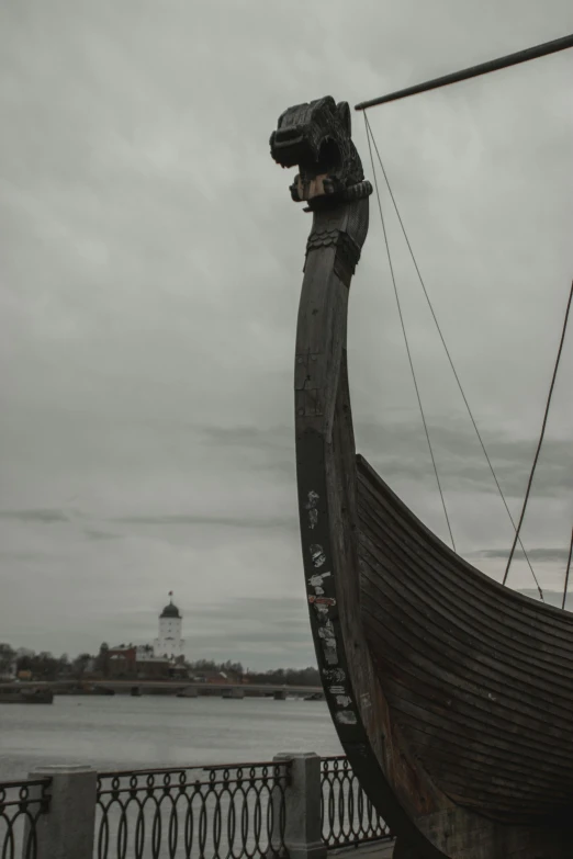 the bow of an ancient viking boat in front of a lighthouse