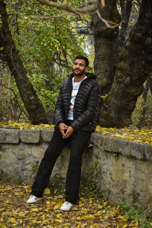 a man with a beard sitting on a stone wall