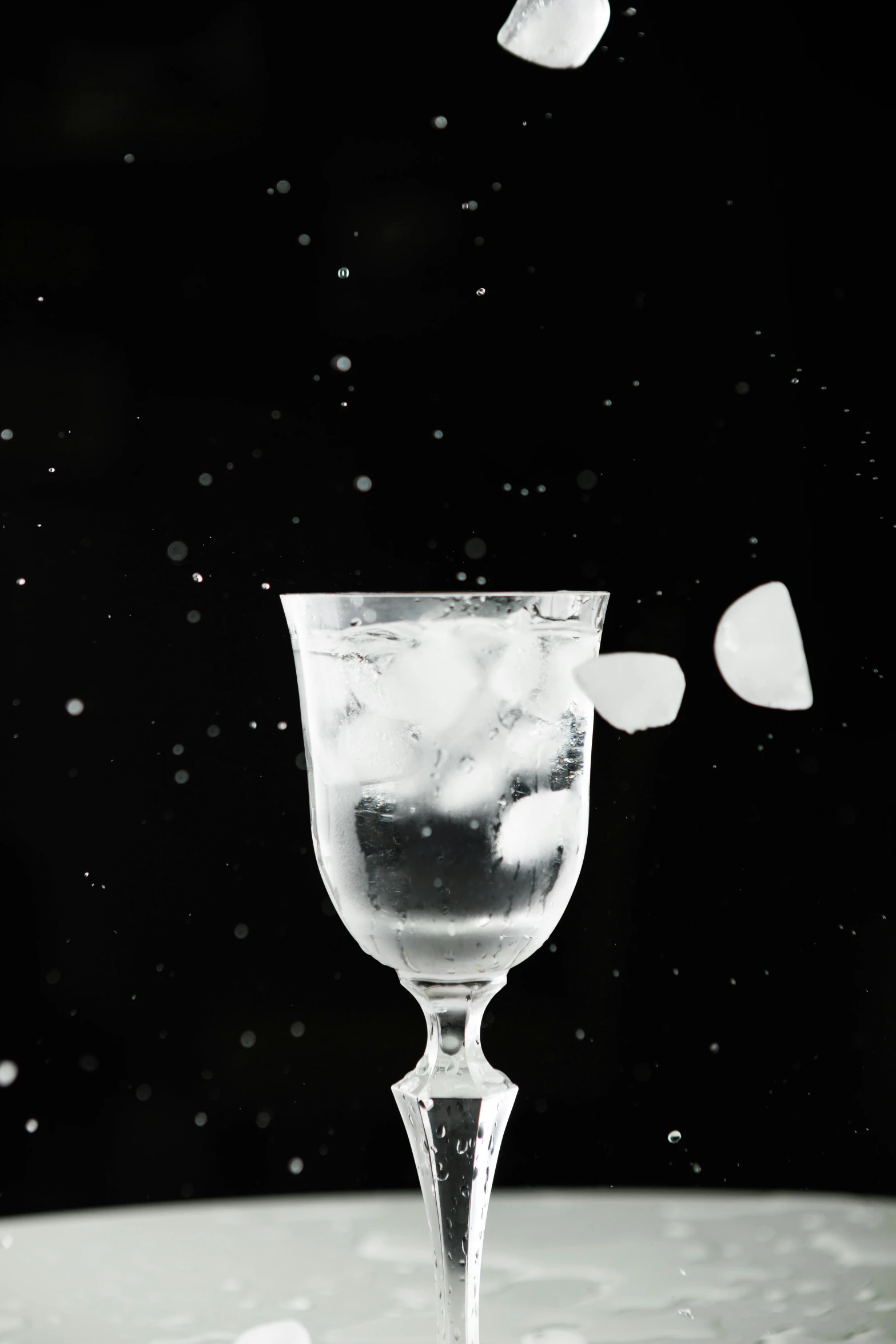 a glass filled with ice with drops falling from it