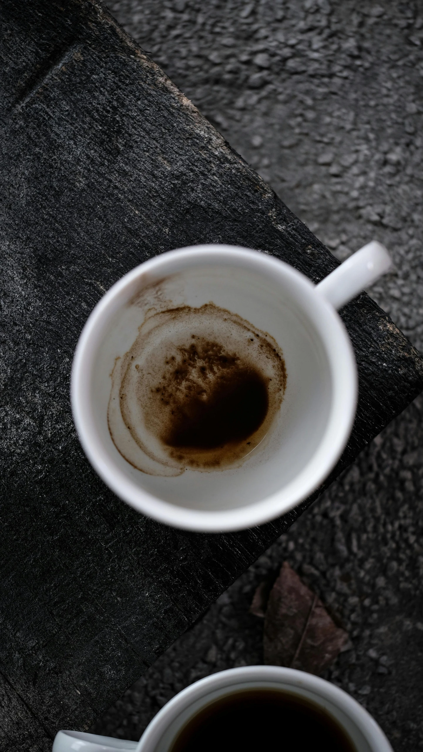 coffee cup sitting next to two spoons on top of a black mat