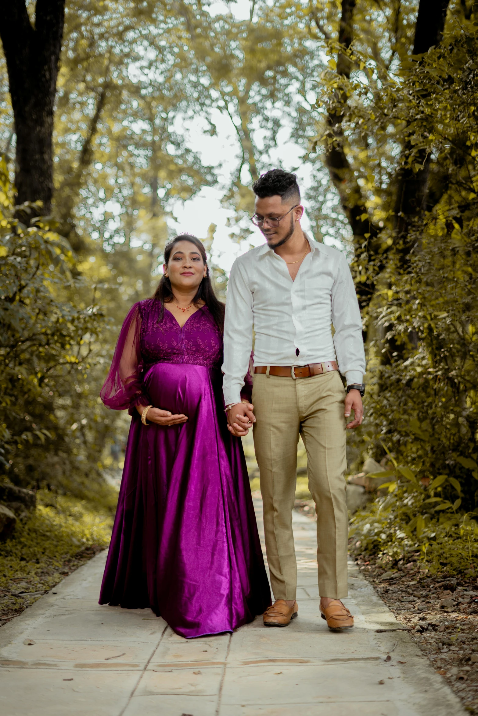 a pregnant woman in a long purple dress and a man dressed in a white shirt