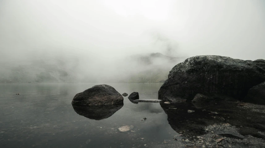 a foggy lake with rocks, and water