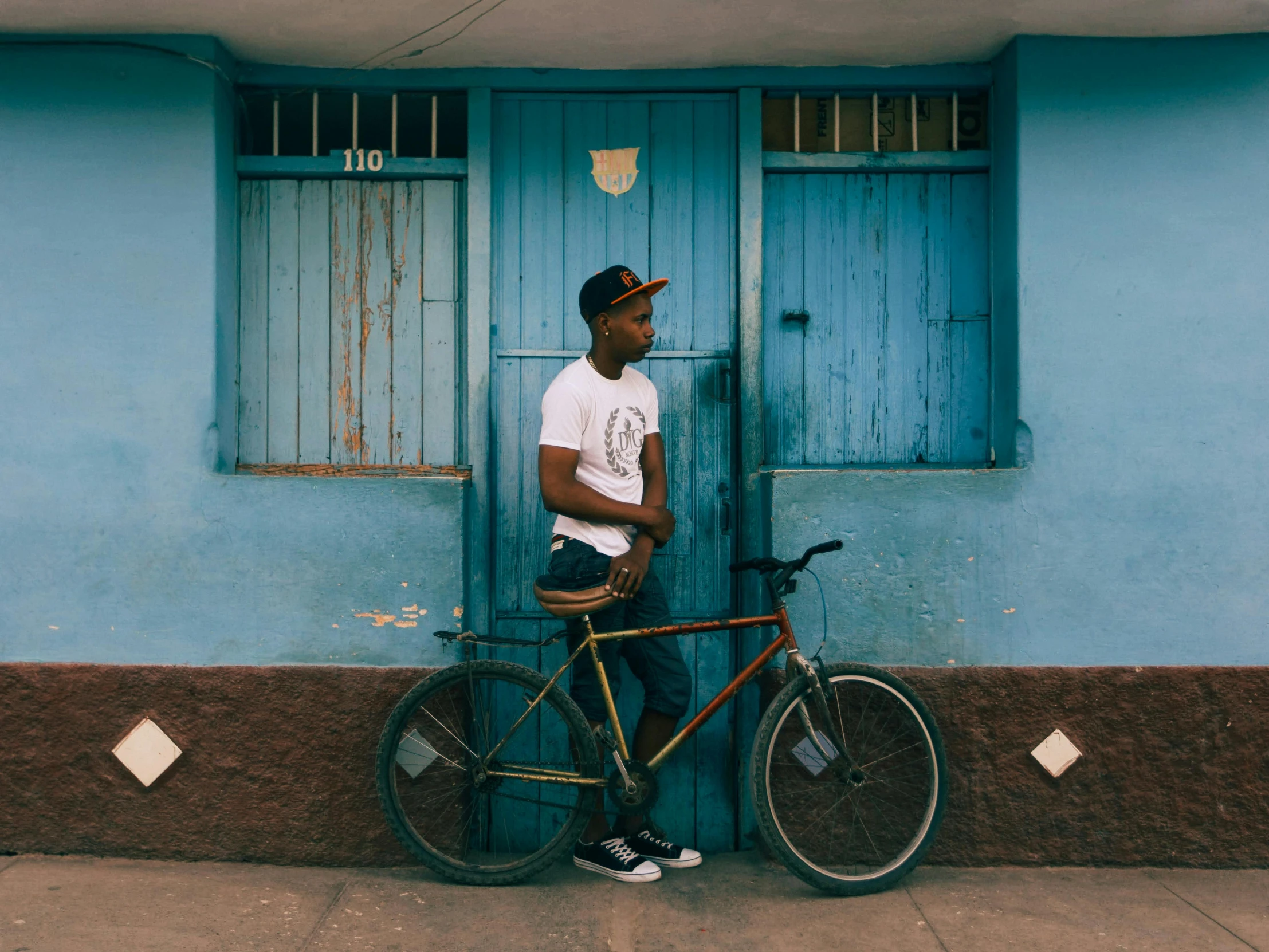 a man leaning on a bike and standing in front of a building