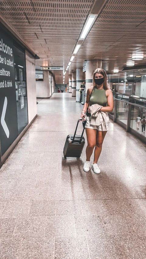 a woman wearing a mask pulling a luggage bag