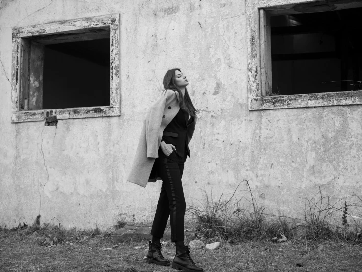 black and white pograph of woman leaning against an abandoned building