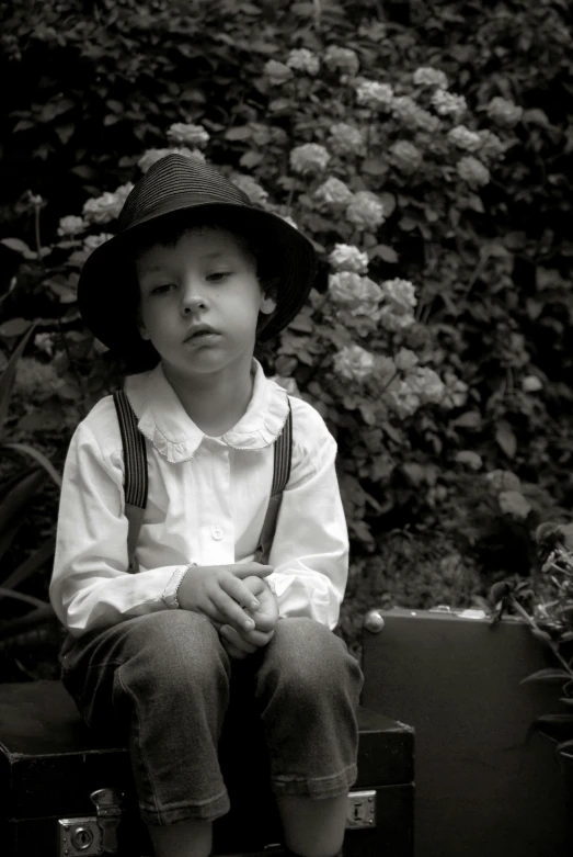 a small boy wearing a hat is sitting on suitcases