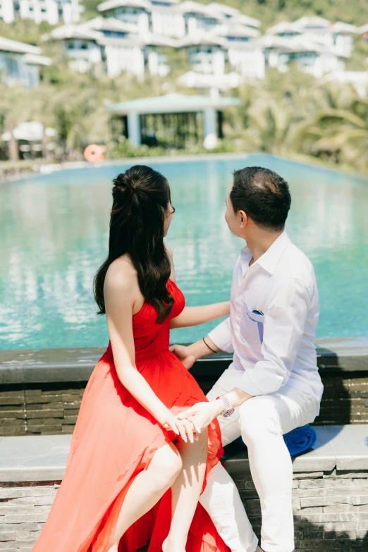 a couple sit together by a large pool