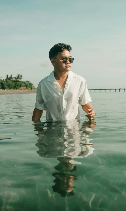 a man wearing sunglasses standing in the water