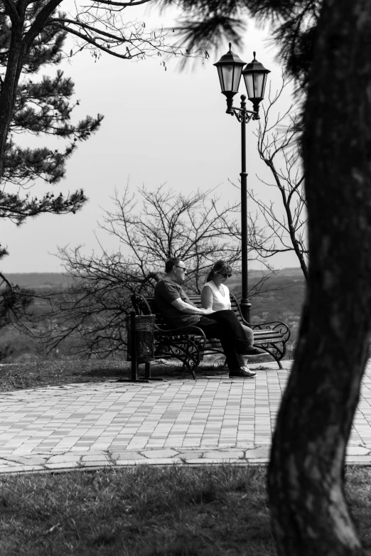 an older couple sit on a bench and talk