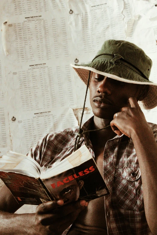 man wearing hat reading a book on bed