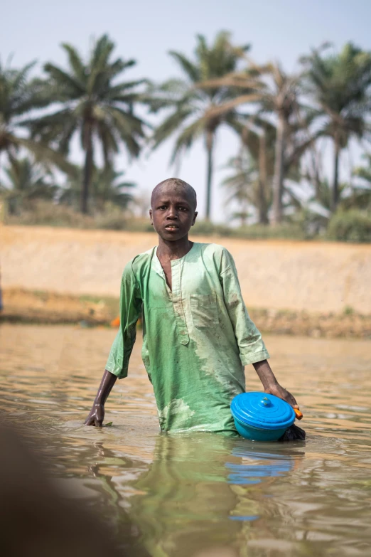 man walking in water holding blue frisbee