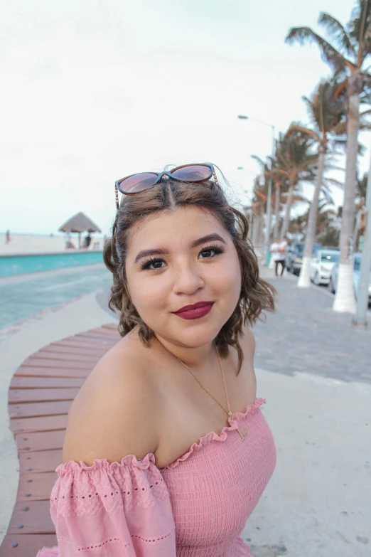 woman in off - the - shoulder pink dress and dark shades, on boardwalk