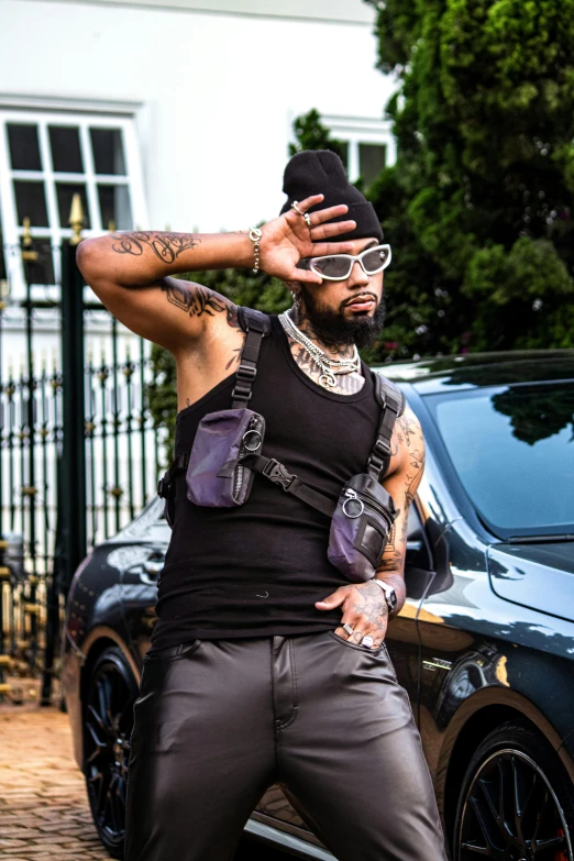 a man wearing all black is standing in front of a car