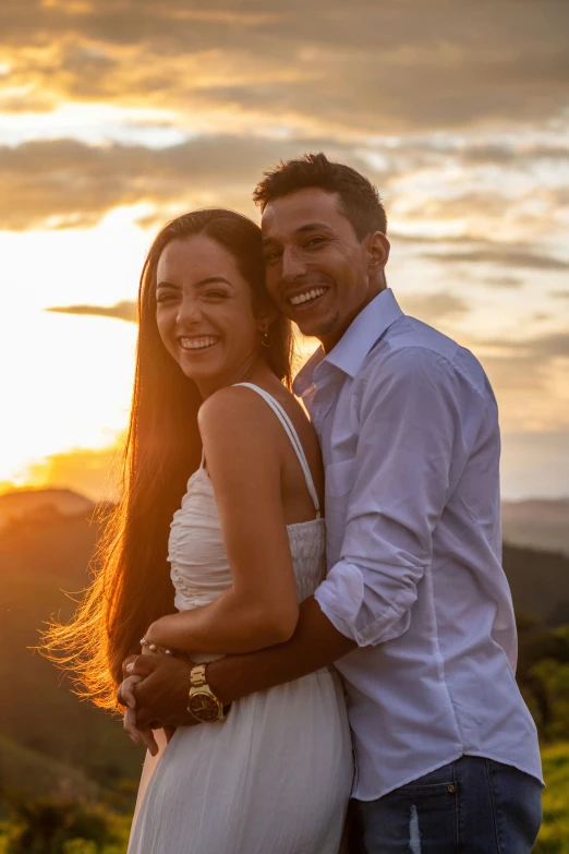 couple standing in front of sunset at the top of a mountain