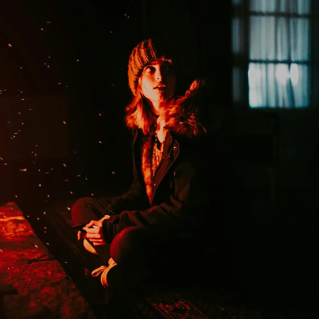 a woman sitting next to a lit fire