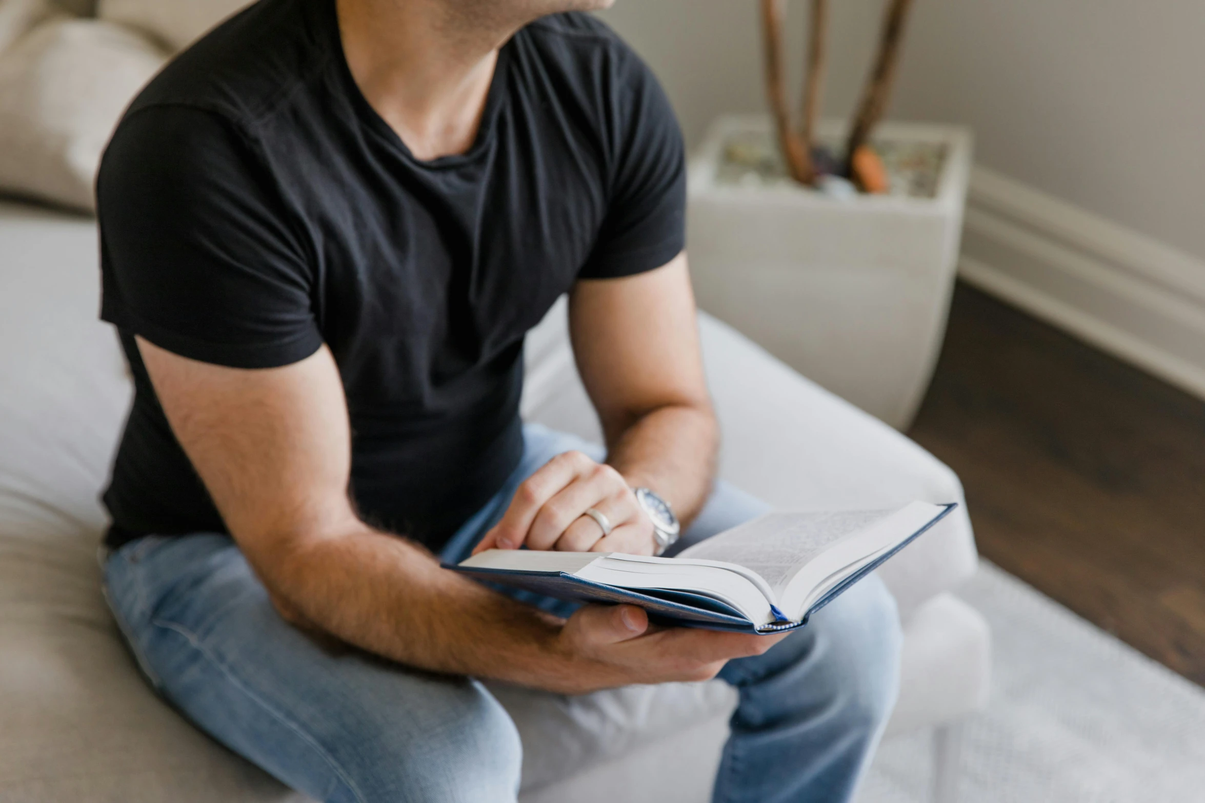 a man sitting on a bed reading a book