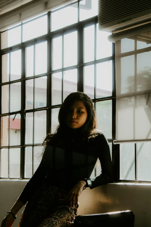 a woman sitting next to a window in a room