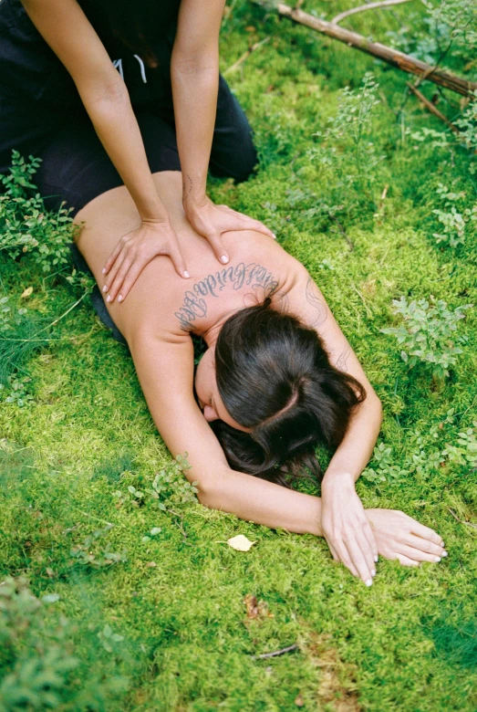 a woman has her back on the ground while she holds the foot of another person