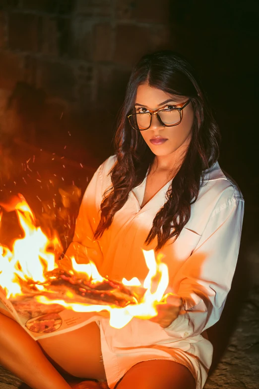 a woman in a white robe holding a pizza in front of flames