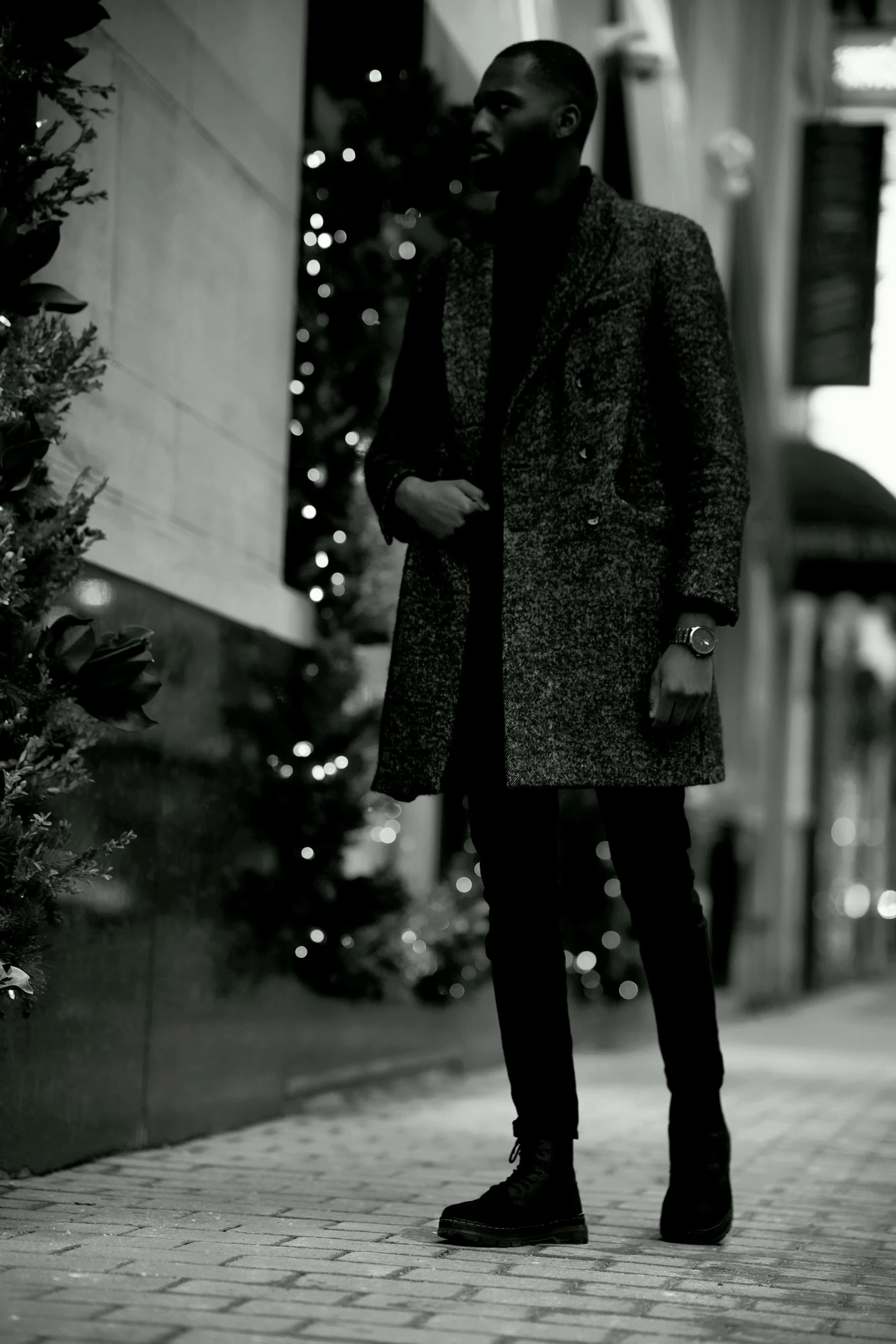 a man in black jacket standing next to a building