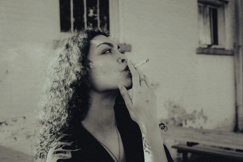 a woman smokes a cigarette near an old building