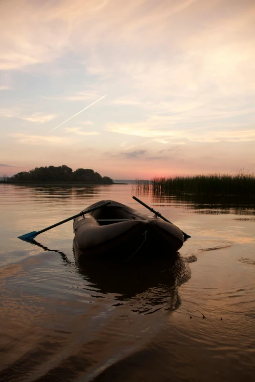 an empty canoe in the water and someone paddling