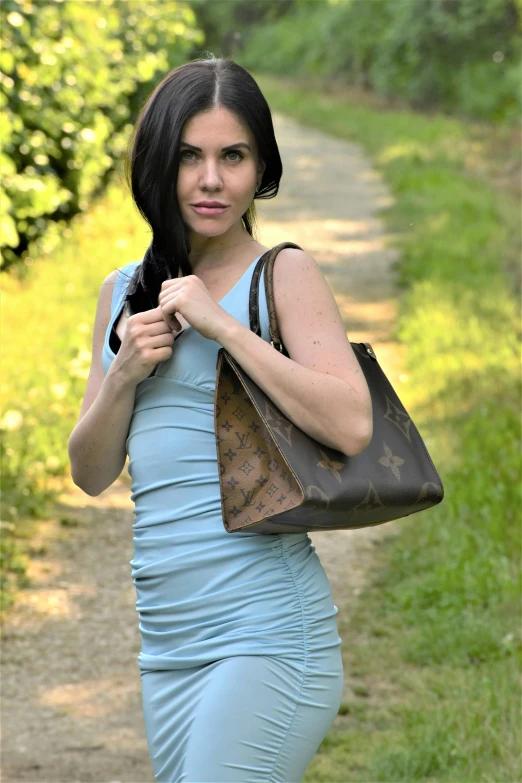 a young woman wearing a blue bodysuit and carrying an open brown bag
